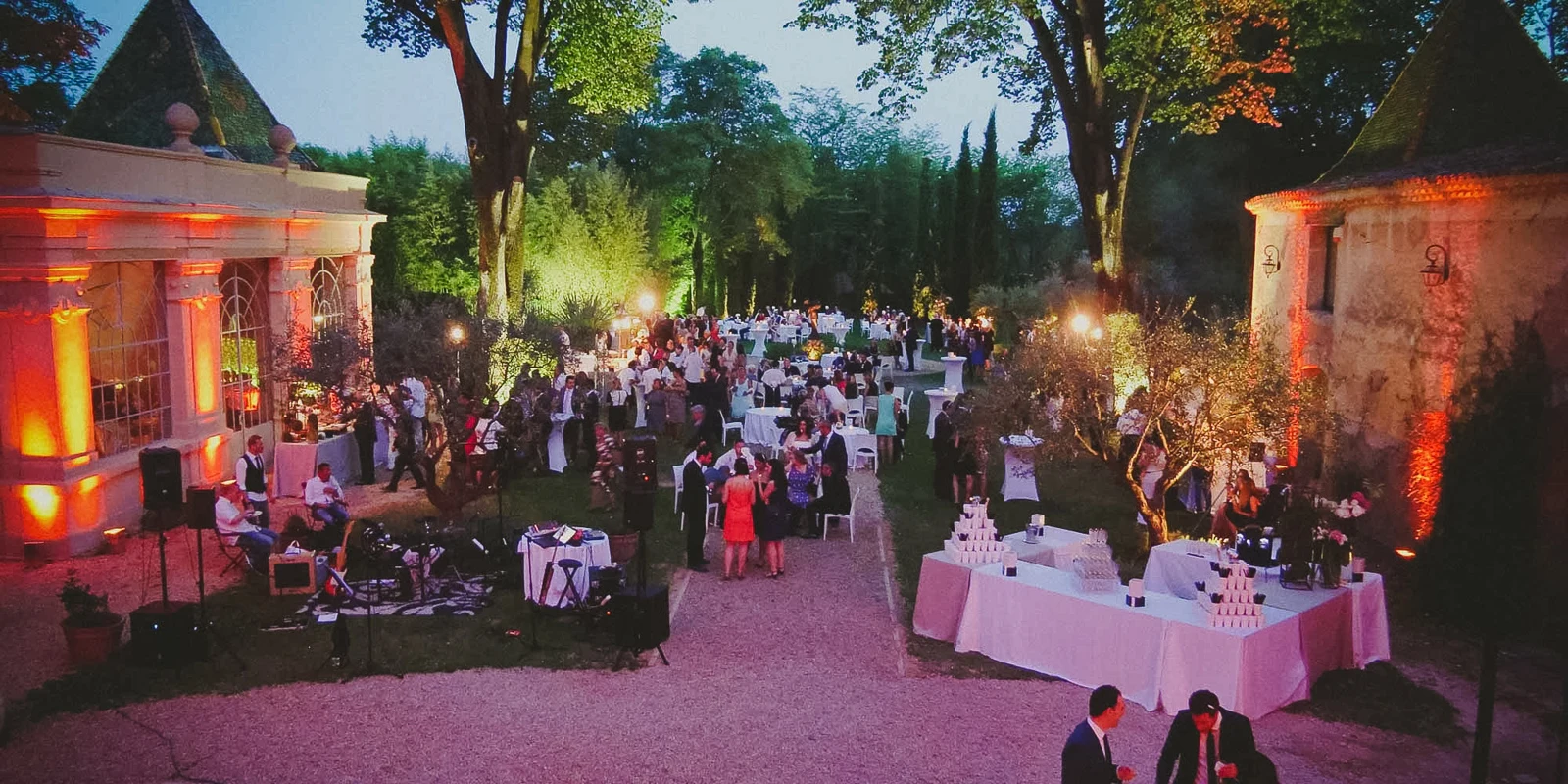 Abendliche Hochzeitsfeier im Garten eines Châteaus in der Provence, warmes Licht und feiernde Gäste