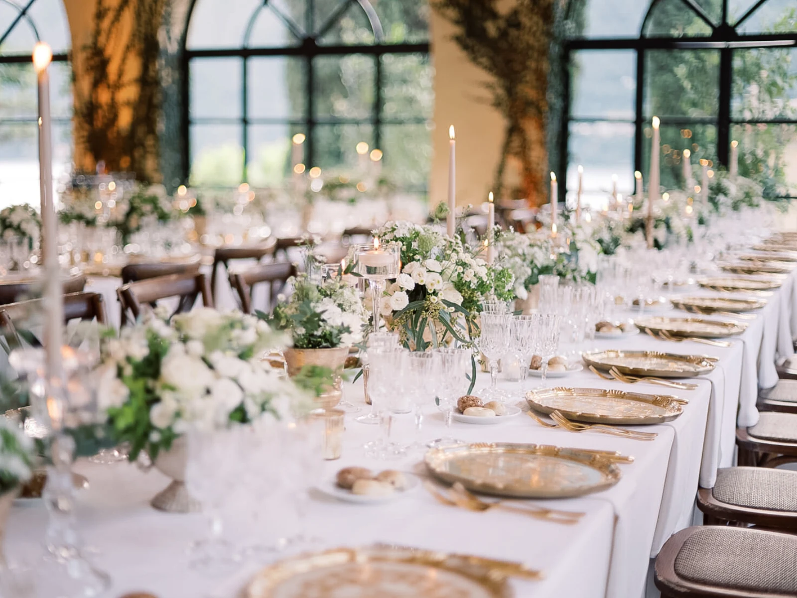 Elegant gedeckte Hochzeitstafel in einer Orangerie in Italien, mit Kerzen und Blumenschmuck